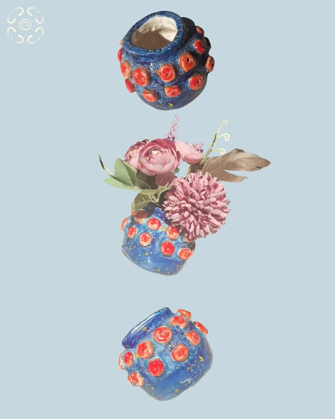 Tres vasos de cerámica azules con relieves rojos, uno con flores